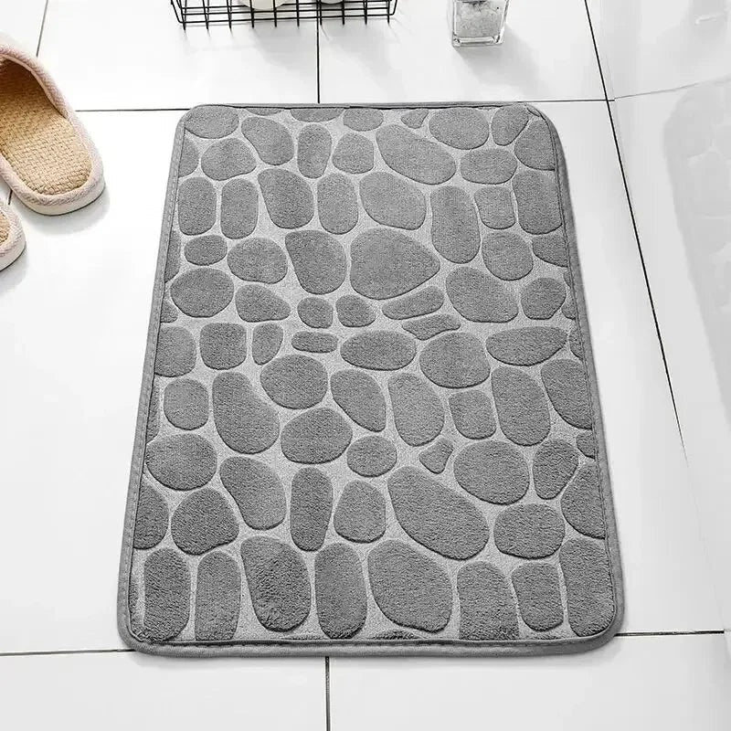 Alfombrilla de baño gris con diseño de guijarros de Variedad Online. Textura suave y absorbente.