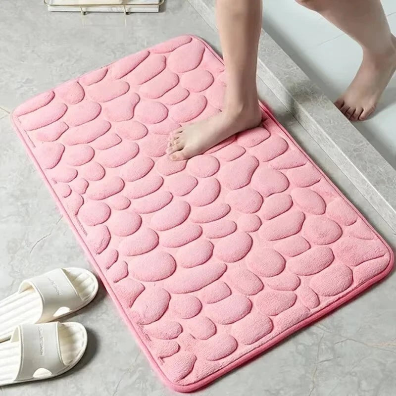 Alfombrilla de baño rosa de Variedad Online con diseño de guijarros, suave y absorbente.