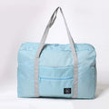 Bolsa de viaje plegable azul claro de nailon resistente al agua de Variedad Online con bolsillo frontal con cremallera y asas grises.