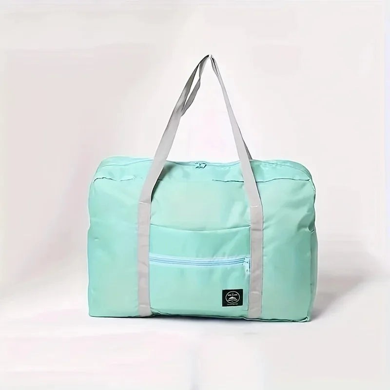 Bolsa de viaje plegable de nailon color menta de Variedad Online con bolsillo frontal con cremallera y asas grises.