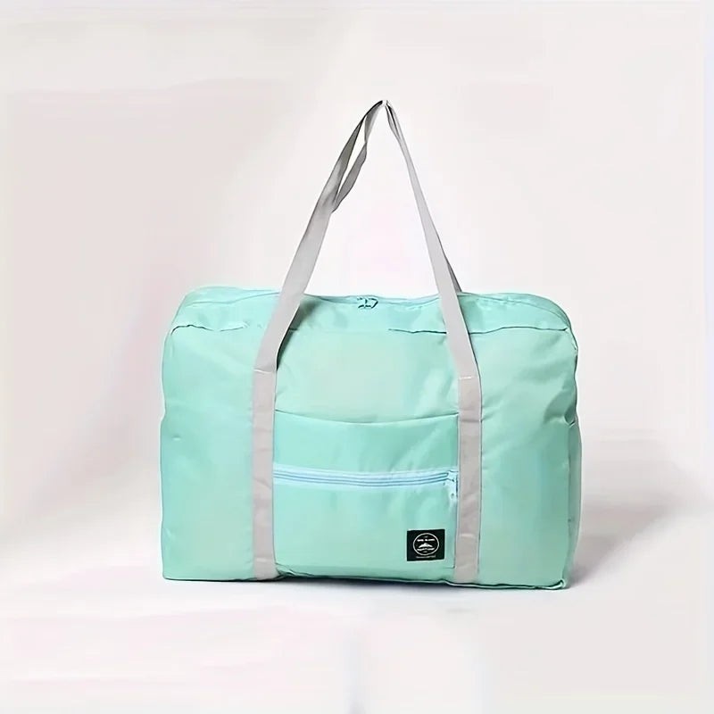 Bolsa de viaje plegable de nailon color menta con asas grises y bolsillo frontal con cremallera de Variedad Online.