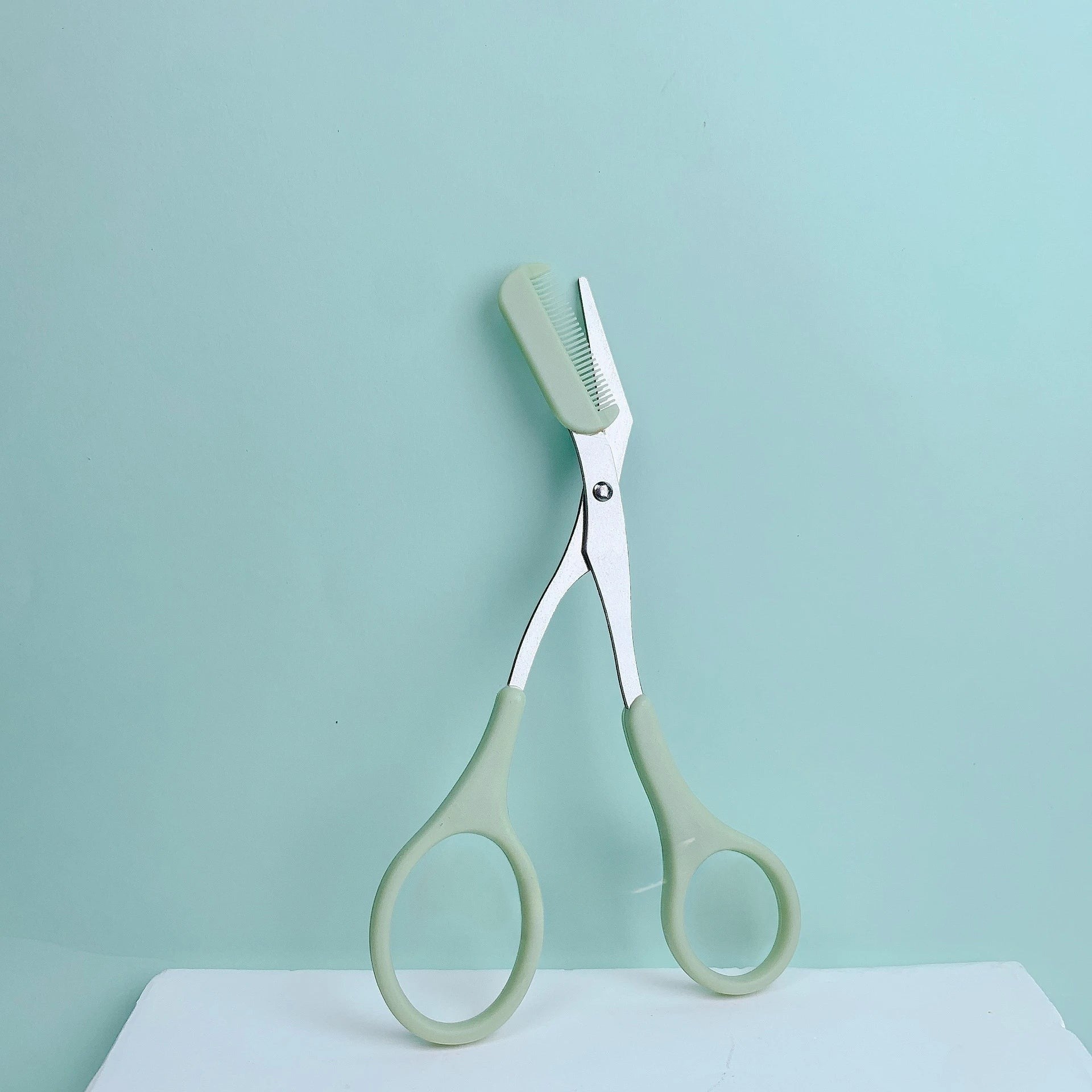 Variedad Online tijeras para cejas color verde menta con peine integrado para dar forma y recortar cejas con precisión.
